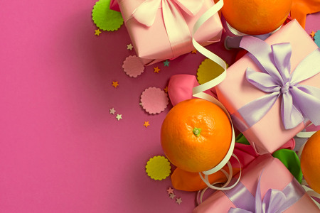 Decorative composition Three boxes with gifts Satin ribbon Bow Oranges Confetti Serpentine birthday party. The view from the topの写真素材