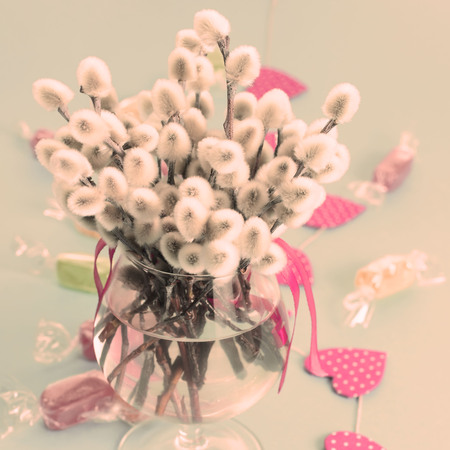 Festive arrangement in a Glass vase with twigs catkins. Bright Candy garlands on a pink background.の写真素材