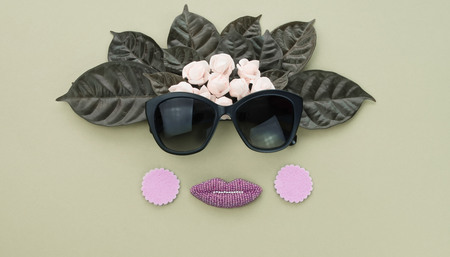 Surrealism Banner Background for text, the imitation of facial concept. Sunglasses natural leaves and white flowers on a green background. Flat lay top viewの写真素材