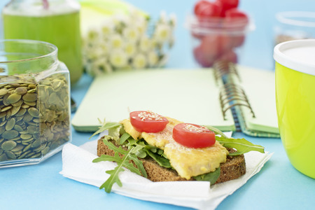 Healthy vegetarian Breakfast Sandwich grain bread tofu cheese, detox smoothie, pumpkin seeds, cherry tomatoes, natural flowers, blue background, notebook, Lunch box soup for lunch.の写真素材