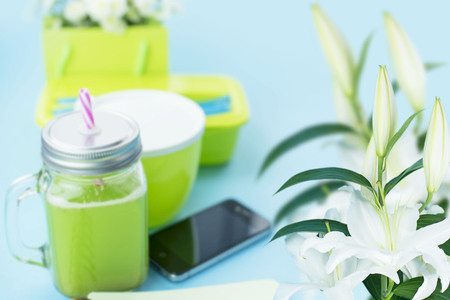 Healthy vegetarian Breakfast. Sandwich Grain bread with herbs and tofu, detox smoothie, apple, sunflower seeds, cherry tomatoes, fresh natural flowers, blue background, smartphone. Copy space for textの写真素材