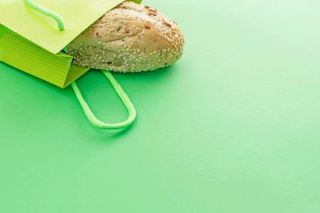 Fresh crusty bread in the shopping bag on a green background. Copy space for your text