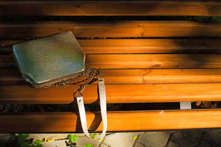 Beautiful bag for women, lying on a wooden bench. A warm summer evening
