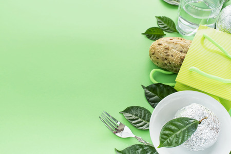 A set of ecological healthy products fresh bread water glass apple leaves tableware. The concept of healthy eating. Green copy space backgroundの写真素材