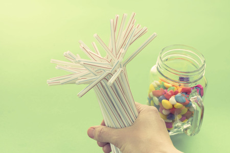 set of tubes for a cocktail caramel colored glass Cup female hand on a green background. Party and holiday accessoryの写真素材