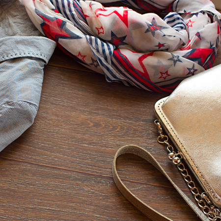 Items of women's wardrobe on wooden background. Trendy striped blazer with brooch and a light scarf. The concept of fashion and designの写真素材