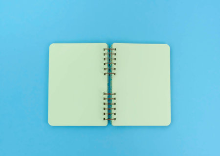 Open notebook for notes is on the surface. The pastel blue background copy space
