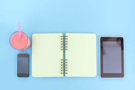 The opened notebook for records lies on the surface of the cocktail pink glass tube bouquet chrysanthemum  tablet box gift. The pastel blue background copy spaceの写真素材