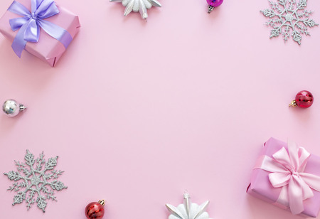 Christmas composition Flat lay boxes with gifts satin ribbon bow Christmas toys snowflakes. Decorative frame top view pink backgroundの写真素材