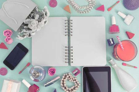 Festive background poster gift box with a satin ribbon bow flower bouquet pearl jewelry laptop tablet smartphone cosmetics lipstick perfume nail cocktail glass tube, the background is blue. Top view copy space flat layerの写真素材