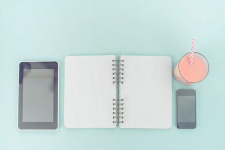 The opened notebook for records lies on the surface of the cocktail pink glass tube bouquet chrysanthemum perfume tablet box gift. The pastel blue background copy spaceの写真素材