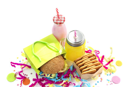 Festive composition of drinks, snacks, holiday hamburger, cookie, tinsel, confetti, gift box, cocktail and saturated colors. Children's holiday birthday partyの写真素材