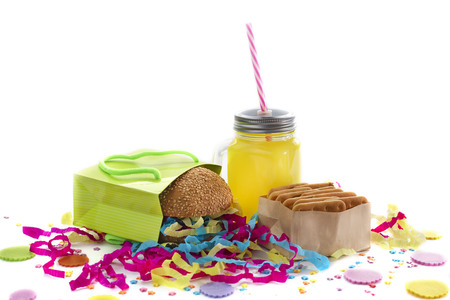 Festive composition of drinks, snacks, holiday hamburger, cookie, tinsel, confetti, gift box, cocktail and saturated colors. Children's holiday birthday partyの写真素材