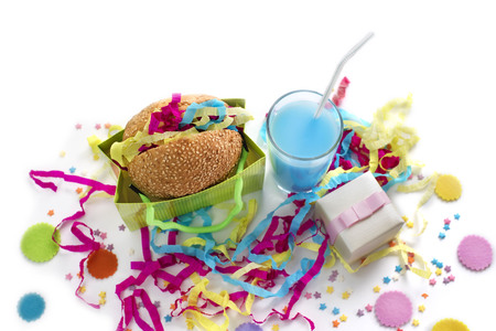 Festive composition of drinks, snacks, holiday hamburger, cookie, tinsel, confetti, gift box, cocktail and saturated colors. Children's holiday birthday partyの写真素材