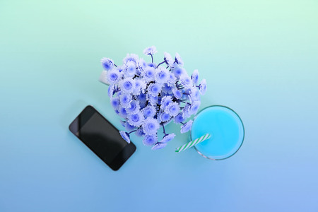 Surrealism bouquet of chrysanthemum flowers in a cup of tea glass cocktail and phone. Festival green backgroundの写真素材