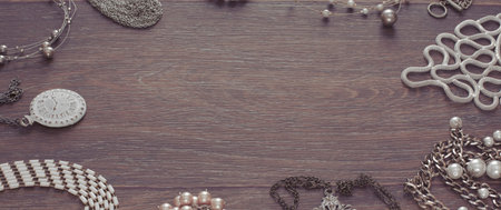 Banner Set of vintage jewelry on a dark wooden background. Necklace pearl cameo locket watch view...