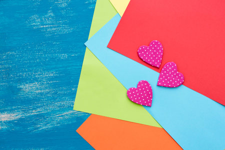 Colored sheets of paper on a wooden painted blue background decorative heart Valentine's day....