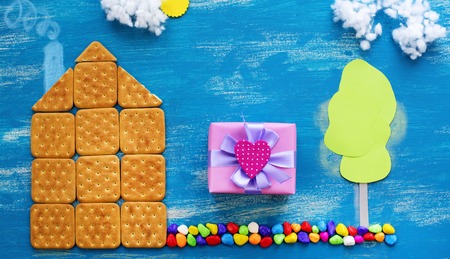 Banner concept of a cookie house on a wooden blue sky cloud background family path. Top view Flat layの写真素材