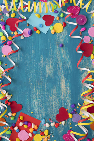 Decorative holiday background with streamers confetti candy hearts decor. Blue shabby wooden top view background flat layの写真素材