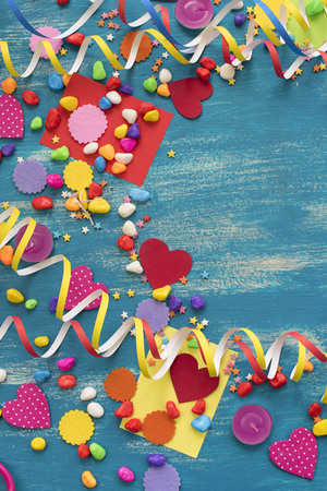 Decorative holiday background with streamers confetti candy hearts decor. Blue shabby wooden top view background flat layの写真素材