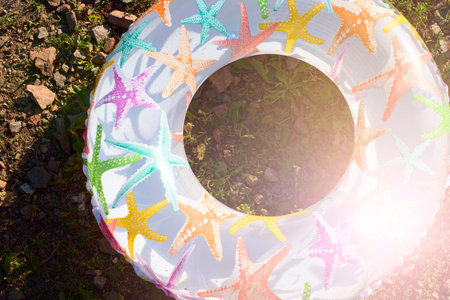 Bright children's inflatable circle lying on the ground on the beach. Lifeline is white with a...