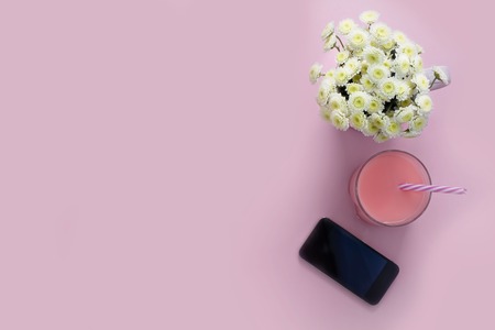 Composition flat lay pink background mobile phone flowers chrysanthemum glass cocktail straw Top view copy spaceの写真素材