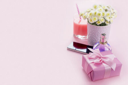 Composition flat lay gift to a woman Modern gadget mobile phone glass cocktail perfume bouquet of flowers Preparing for the holiday surprise gift box pink backgroundの写真素材