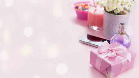 Banner Composition flat lay gift to a woman Modern gadget mobile phone glass cocktail perfume bouquet of flowers Preparing for the holiday surprise gift box pink backgroundの写真素材