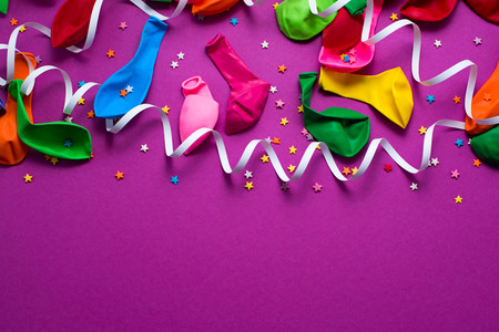 Festive background of purple material colorful balloons streamers confetti. Top view flat lay copy spaceの写真素材