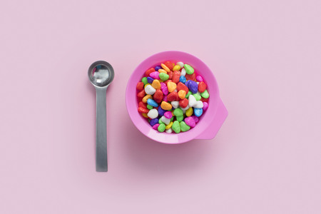 Concept pink plate on pastel pink background food multi-colored metal spoon. Top view flat lay copy space.の写真素材