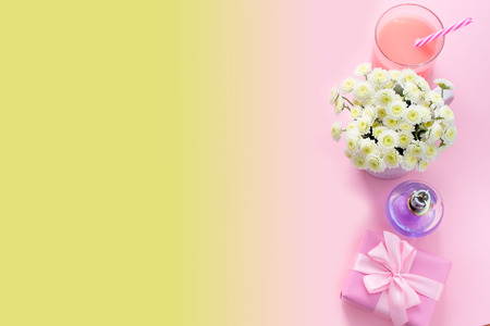 Composition flat lay gift to a woman. Glass cocktail perfume bouquet of flowers. Preparing for the holiday surprise gift box. Top view pink backgroundの写真素材