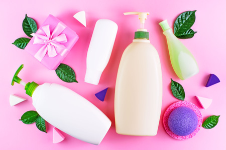 Cosmetic packaging plastic bottle shampoo cream shower gel milk green leaves sponge box gift bow. Natural organic product skin and hair care shopping. Top view pink flat lay background.の写真素材