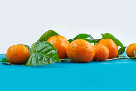 Ripe tangerines with green leaves on a bright blue background copy space selective focus