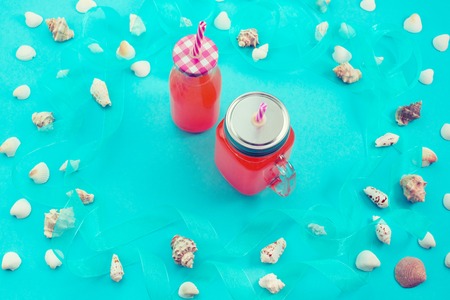 Different sea shells on blue background drink bottle. Top view flat layの写真素材