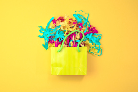 Paper bag with colored streamers on a bright yellow background. A top view of Flat layの写真素材