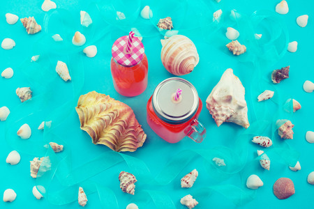Different sea shells on blue background drink bottle. Top view flat layの写真素材
