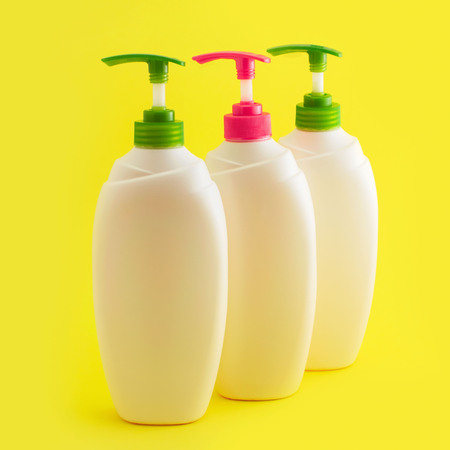 Three plastic bottles with dispenser on yellowの写真素材