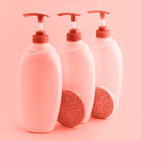 Three plastic bottles with dispenser on coral background.の写真素材