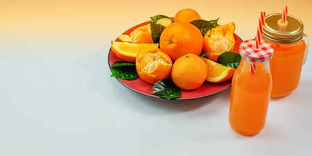 Banner Red plate with oranges and tangerines green leaves bottle with juice on light background. Top view copy spaceの写真素材