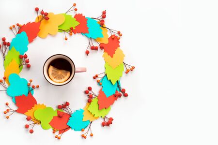 Autumn composition mug with hot tea and lemon. Paper colored leaves branches berries on white background. The concept of autumn. flat lay top viewの写真素材
