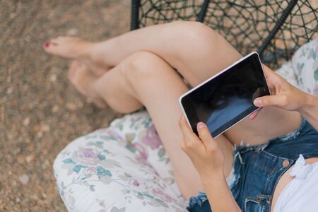View of the girl from above female legs in the hands of a tablet.の写真素材