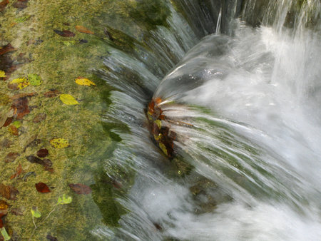 Close-up view of waterfalls on Plitivce lakes, Croatia, with some autumn foliage floating in water