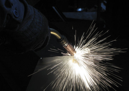 Man welding in a factory with sparks flying around