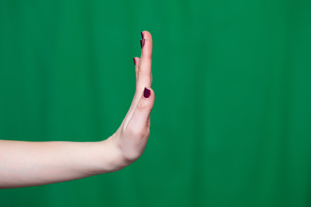 Female hand gesture stop on a green backgroundの写真素材
