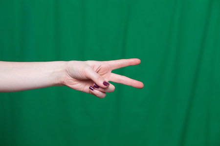 Hand female with two fingers, the world closeup on a green backgroundの写真素材