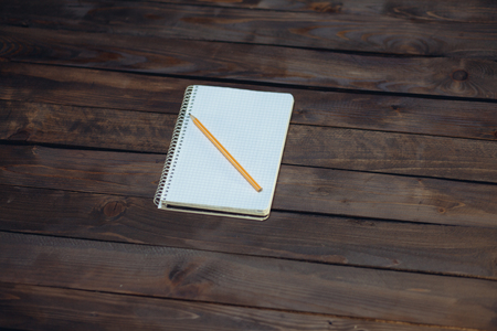Notebook in a cage and yellow pencil on a wooden backgroundの写真素材