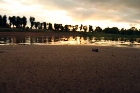 The sand on the beach next to the river and against setting sun in summer vechromの写真素材