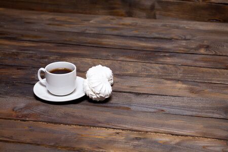 White cup of coffee with two white marshmallow on wooden backgroundの写真素材
