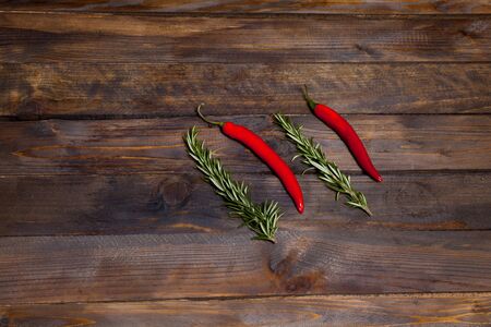 Red chili peppers and green rosemary on wooden backgroundの写真素材