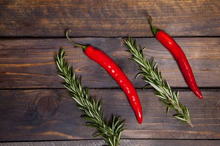 Red chili peppers and green rosemary on wooden backgroundの写真素材